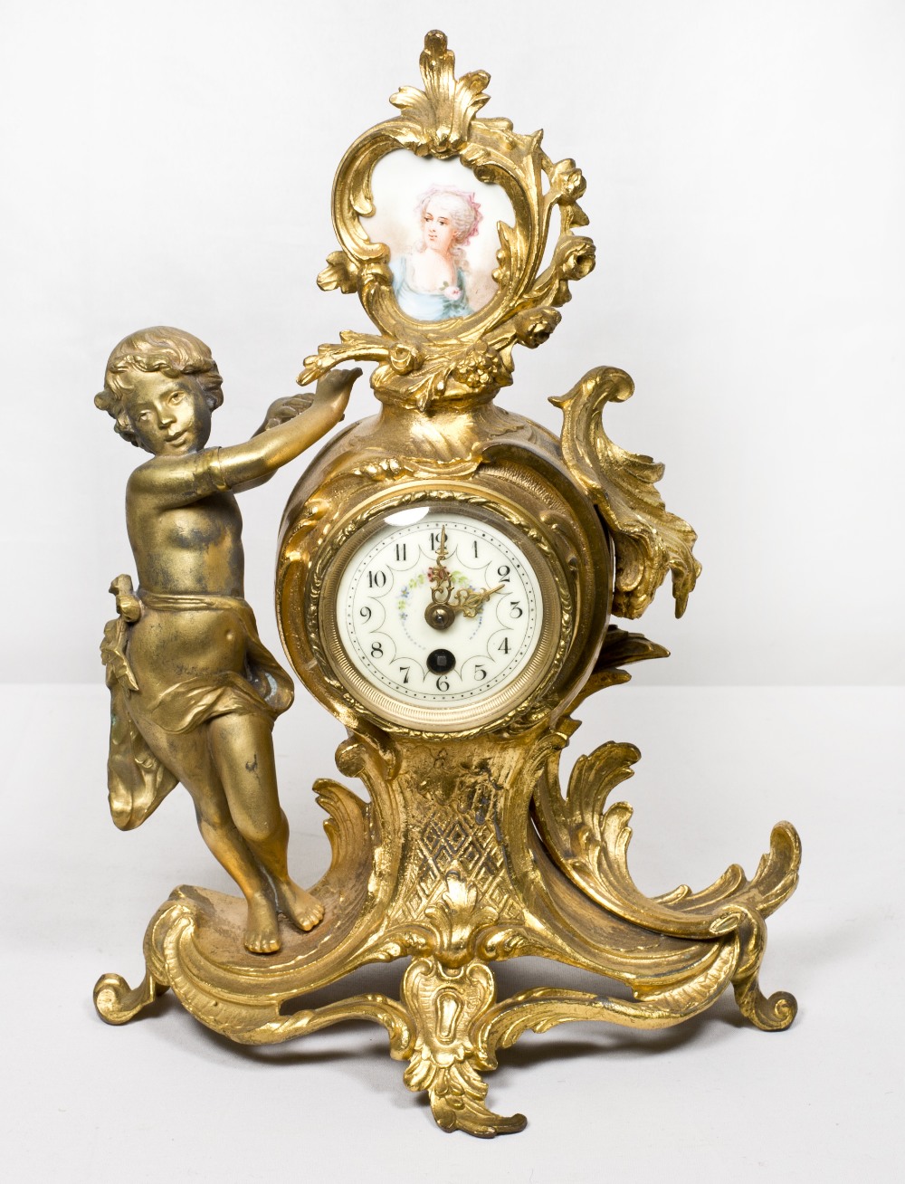A 19th Century mantel clock with white enamel dial, in a gilded spelter case, the top inset portrait