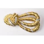 An 18ct. gold brooch of double knot and loop design set with brilliant cut diamonds, signed to the