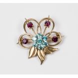 A 9ct. gold brooch of flower and leaf design set blue and red stones
