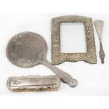 A lady's hand mirror in a silver frame with harebell decoration, a clothes brush with silver back, a