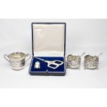 A pair of Mappin and Webb circular silver salts with repousse acorn decoration, on three scroll feet