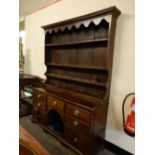 An 18th Century oak dresser the raised back with shaped frieze, fitted shelves with iron cup