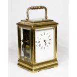 A carriage clock with white enamel dial, repeating movement striking on a gong, in a brass and