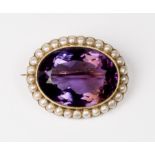 An amethyst brooch of oval form surrounded by seed pearls, in a 15ct. gold frame