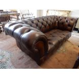 A brown leather Chesterfield, on turned feet