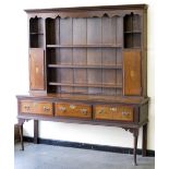 An antique oak dresser, the raised back fitted shelves and two cupboards with shell paterae, the