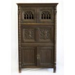 An oak court cupboard with Gothic style decoration, the upper doors with pierced arches, the