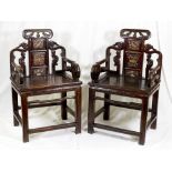 A pair of Chinese chairs with pierced and floral decorated backs, hard seats on square legs and