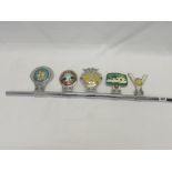 A chrome bar fitted with five car badges comprising:- AA, British Caravan Club, Camping Club, St