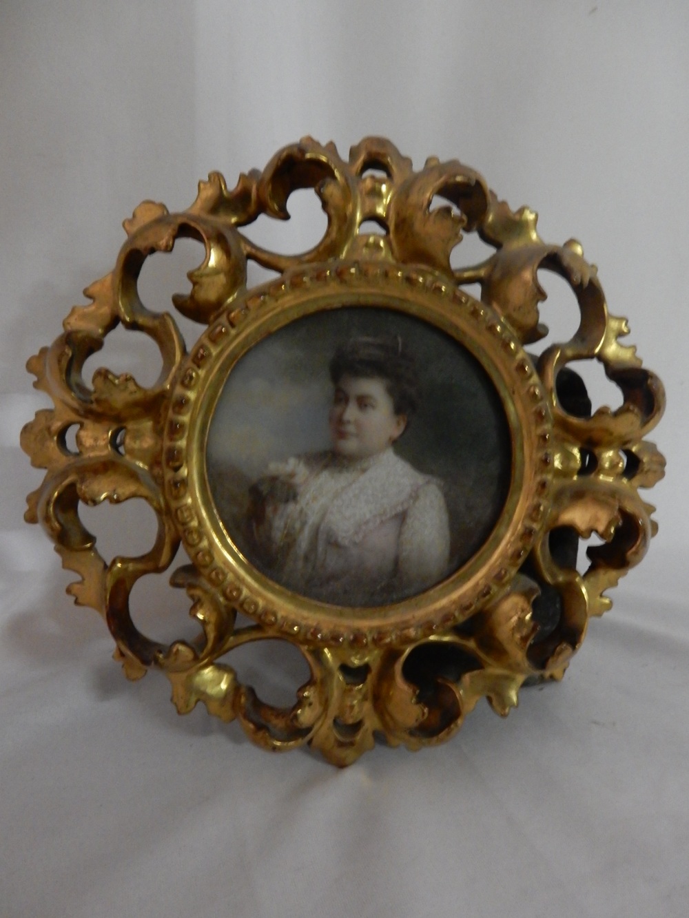 A portrait of an Edwardian lady in pink and lace dress, in a circular Florentine frame and