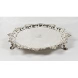 A George II silver card tray with shaped border, family crest to the centre, on three pad feet -