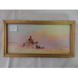 A signed gouache - Desert scene with minarets, figures on camels and beside a river, framed and