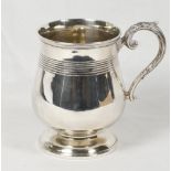 A George III silver mug of baluster form with reeded band of decoration, leaf clad scroll handle -