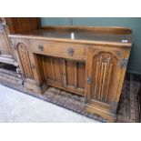 An oak dressing table fitted centre drawer above two cupboards, flanked by doors with linen fold