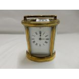 A carriage clock, white enamel dial, in an oval brass and bevelled glass case - 4 1/2in. high