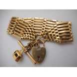 A 9ct. gold wide gatelink bracelet with heart shaped padlock with 'T' bar and charm