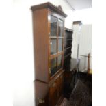 An Edwardian walnut finished bookcase, the upper part fitted two glass doors, the base fitted drawer