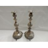 A pair of silver candlesticks with half flued and repousse decoration of flowers and leaf scrolls,