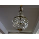 A brass framed basket form chandelier with faceted cut drops