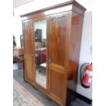 An Edwardian mahogany and inlaid bedroom suite comprising:- triple wardrobe enclosing hanging space,