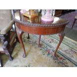 A mahogany half round card table with gadroon border, on cabriole legs terminating in claw and