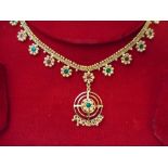 An Indian 21kt. gold necklace set with red and green stones to flower design, in fitted case