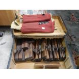 A box of wood working planes, a roll of drill bits and a roll of chisels