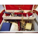 A cream vanity case containing a jewellery box and a selection of costume jewellery including