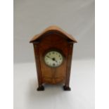 A mantel clock with circular cream enamel dial, in a walnut finished case decorated with inlaid