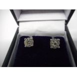 A pair of diamond earrings of cluster form mounted in 18ct. white gold