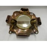 An Arts and Crafts copper and brass framed wall mirror with twin flower form candle arms and two