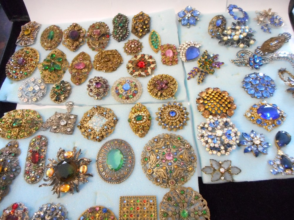 A large collection of coloured paste set brooches