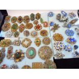 A large collection of coloured paste set brooches