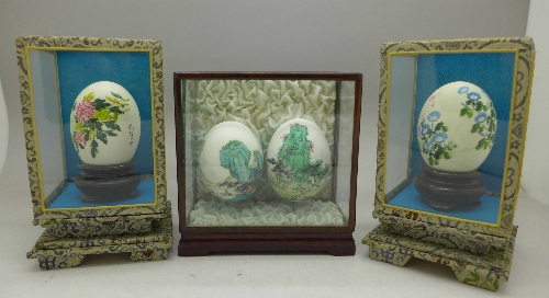 Four Chinese decorated eggs in three display cases