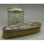A silver topped brush and a silver topped glass jar