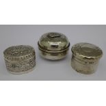 A silver pill box and two white metal pill boxes