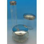 A silver topped hat pin jar and two other silver topped glass jars