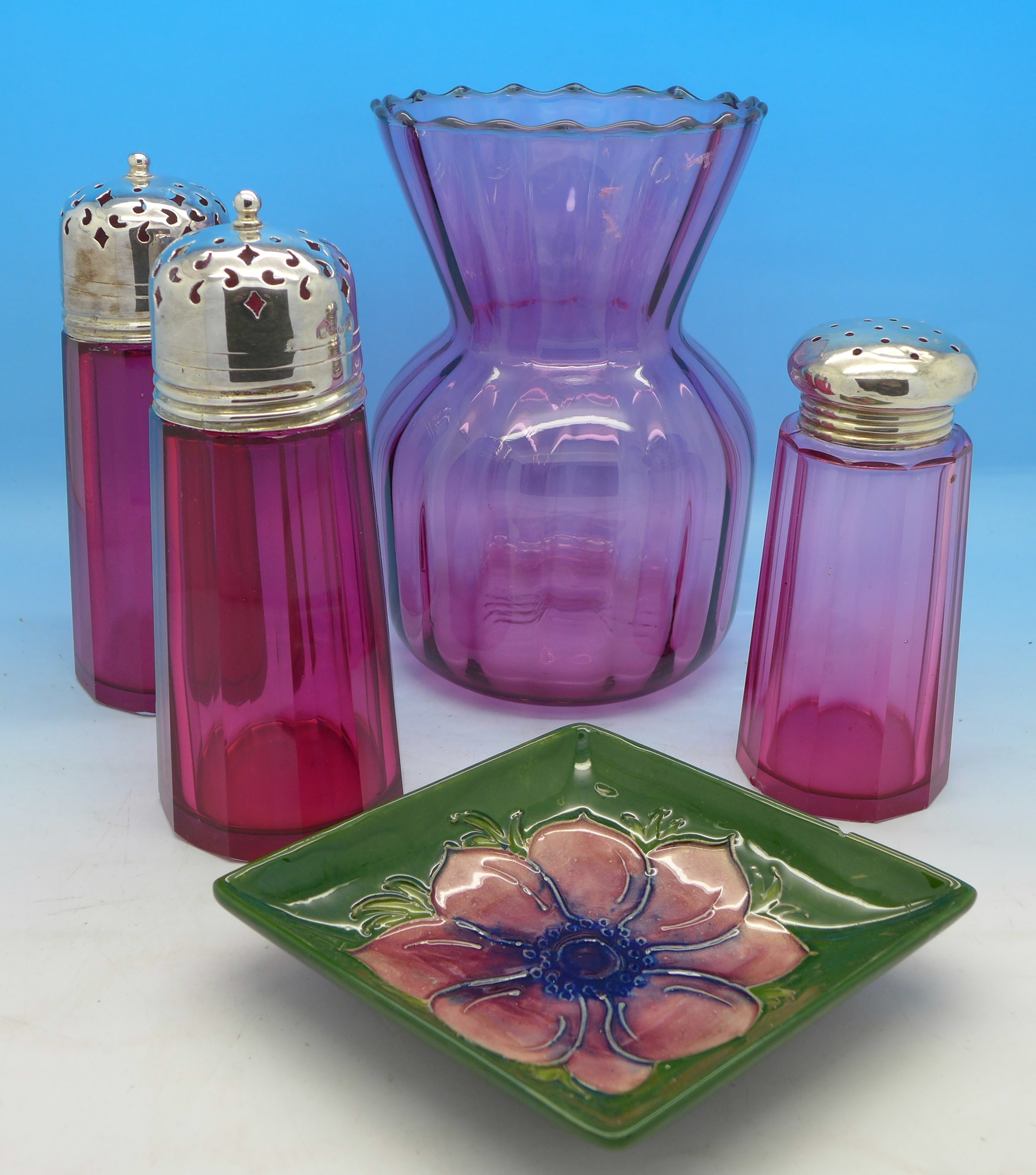 A Moorcroft dish, three cranberry glass shakers, one with a silver top and a glass vase,