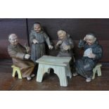 Four continental card playing monk figures,