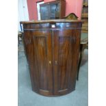 A George IV inlaid mahogany bow-front hanging corner cupboard