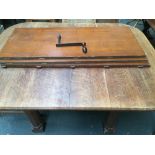 An Oak dining table with extra leaf and winder on five hexagonal legs with hidden castors