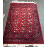 A Persian rug with red fields and cream fringing 220 x 140cm