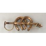 A 9ct gold brooch with two horseshoes and a hunting whip with deer slot handle 0.