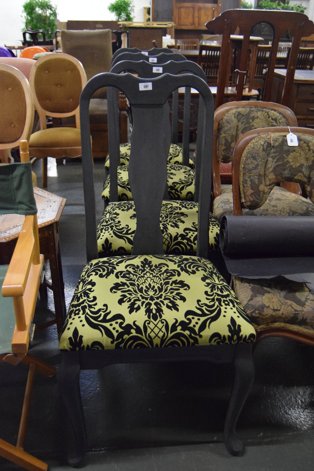 A set of four black painted high back dining chairs with vase shaped splats upholstered in line and