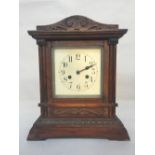 A wooden cased mantel clock with carved pediment,