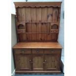 A modern pine Welsh dresser with plate rack and hooks over three short drawers over a pair of