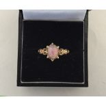 A delicate gold ring with opal stone of pink, gold and blue hue,