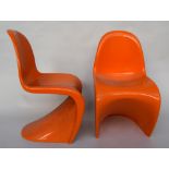 A set of two orange modern fiberglass chairs of contemporary design