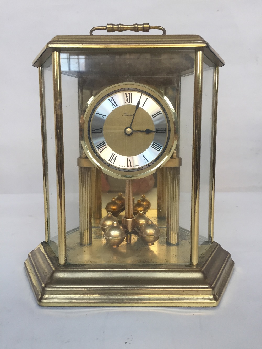 A hexagonal Kienzle torsion clock with Roman numerals on a white and yellow metal dial