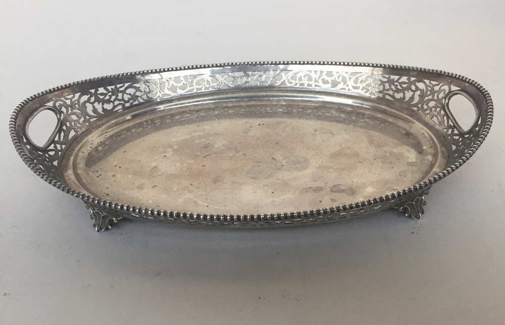 An oval shaped salver on four feet the sides decorated with pierced scrolling foliage and beaded